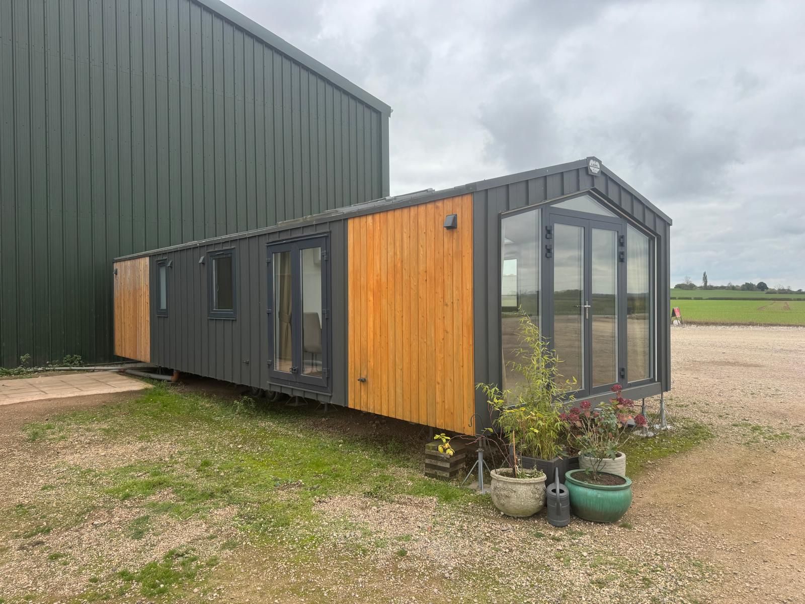 Modern timber-clad lodge sited beside a barn